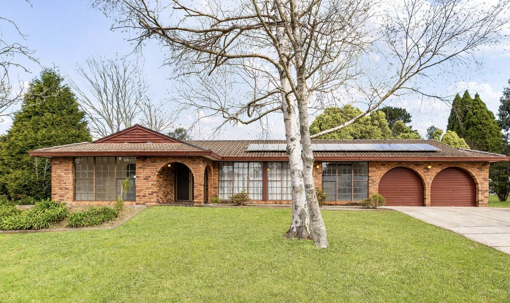 Red-brick front of 1 Erica Road with a lawn, established trees and a double garage