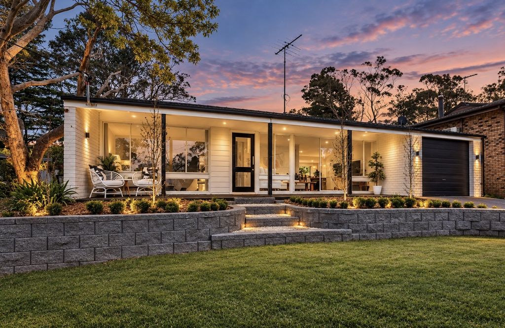 Front of 5 Gladstone Road at dusk: white weatherboard home with a lit verandah, garage and lawn behind a low stone retaining wall