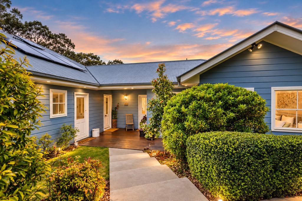 Front entry of 74 Highland Street at dusk, with a lit path, clipped hedges and blue weatherboard walls
